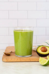 Green avocado smoothie in a glass with mint and lime